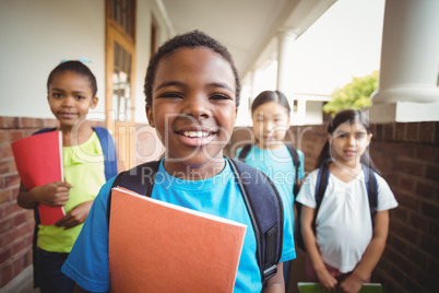 Cute pupils holding notebooks at corridor