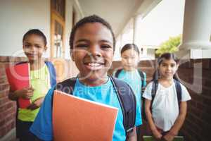 Cute pupils holding notebooks at corridor