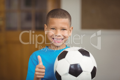 Smiling pupil holding football and doing thumbs up