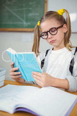 Concentrated pupil reading book at her desk