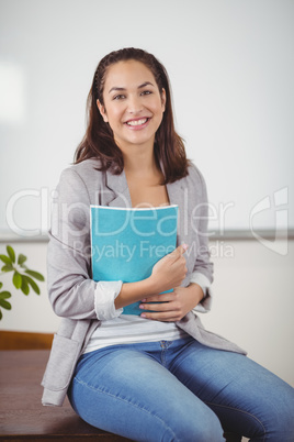 Pretty teacher with notepads sitting on desk