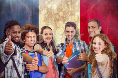 Composite image of smiling group of students doing thumbs up