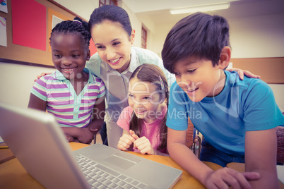 Teacher using laptop with pupils