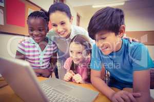 Teacher using laptop with pupils