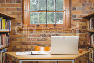 Desk with laptop, glasses and ledger on it