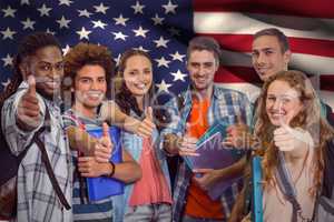 Composite image of smiling group of students doing thumbs up