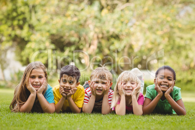 Smiling classmates lying in a row in grass