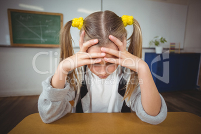 Upset pupil sitting at her desk in a classroom