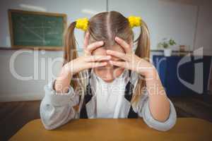 Upset pupil sitting at her desk in a classroom
