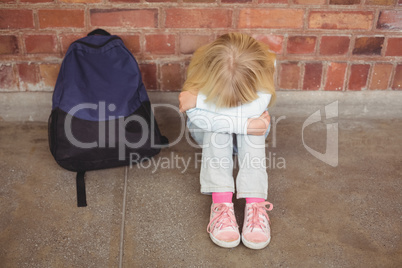 Sad pupil sitting alone on ground