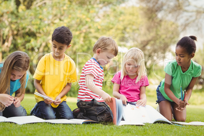 Classmates sitting in grass and reading books