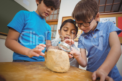 Pupils looking at rock with magnifying glass