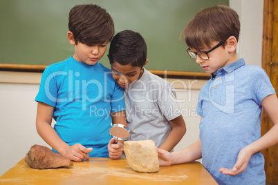 Pupils looking at rock with magnifying glass