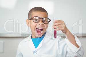 Surprised pupil with lab coat looking at test tube