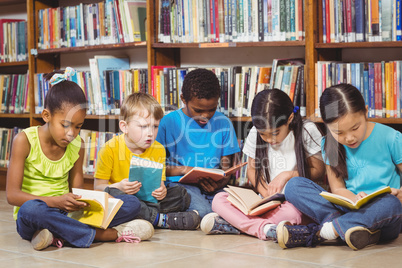 Pupils sitting on the ground and reading books in the library