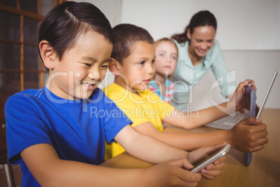 Cute pupils in class using laptop and tablet