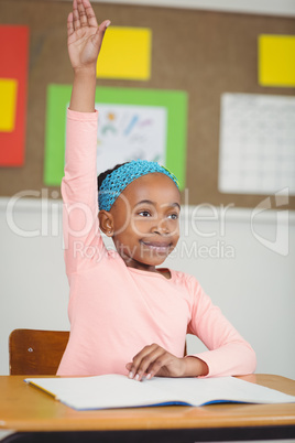 Cute pupil raising hand in a classroom