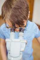 Pupil looking through microscope in class