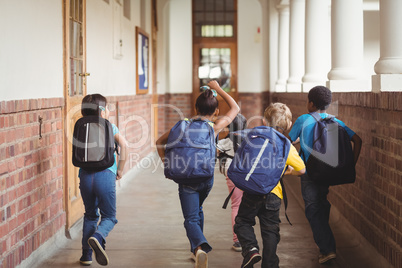 Rear view of happy pupils walking at corridor