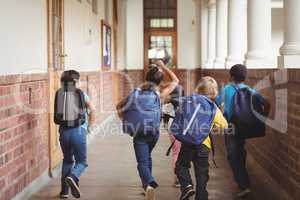 Rear view of happy pupils walking at corridor