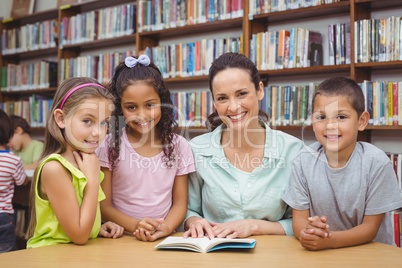 Pupils and teacher reading book in library