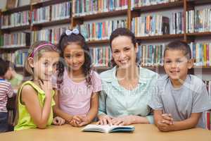 Pupils and teacher reading book in library