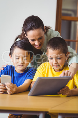 Cute pupils in class using phone and tablet