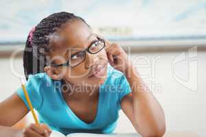 Cute pupil daydreaming at her desk in a classroom
