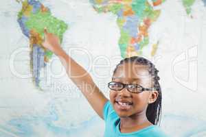 Smiling pupil pointing on world map in a classroom