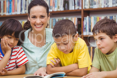 Pupils and teacher reading book in library
