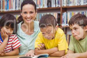 Pupils and teacher reading book in library