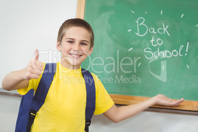 Smiling pupil showing back to school sign on chalkboard