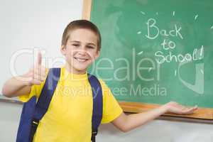 Smiling pupil showing back to school sign on chalkboard