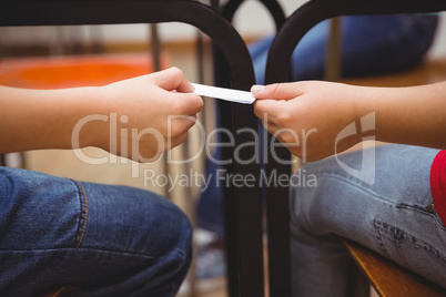 Pupil passing a note to a classmate