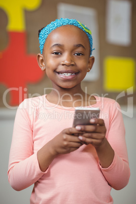 Cute pupil with smartphone in a classroom