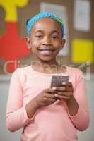 Cute pupil with smartphone in a classroom