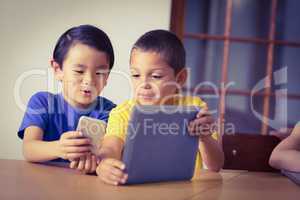 Cute pupils in class using phone and tablet