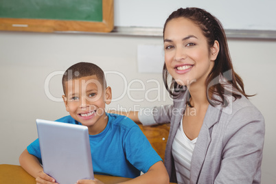 Pretty teacher and pupil with tablet at his desk