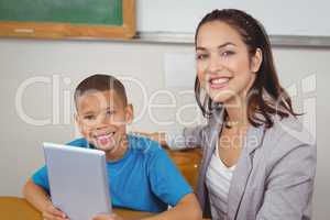 Pretty teacher and pupil with tablet at his desk