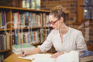 Blonde teacher correcting in the library