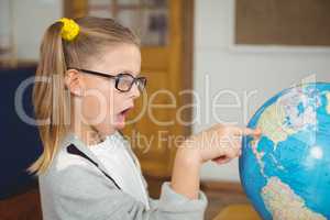 Astonished pupil pointing on globe in a classroom