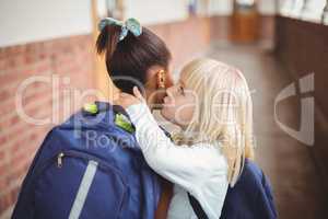 Cute pupils whispering secrets at corridor
