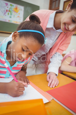 Pupil and teacher at desk in classroom