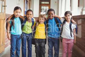 Cute pupils with schoolbags standing at corridor