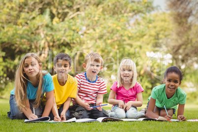 Smiling classmates sitting in grass and studying