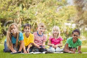 Smiling classmates sitting in grass and studying