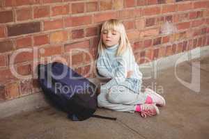 Sad pupil sitting alone on ground