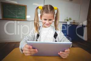 Cute pupil using tablet at her desk in a classroom