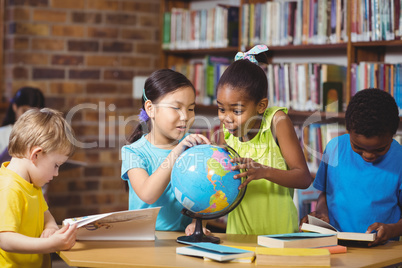 Surprised pupils studying globe in the library