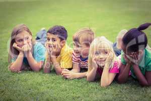 Smiling classmates lying in a row in grass